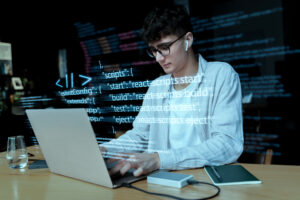 A person working on a laptop, writing a code