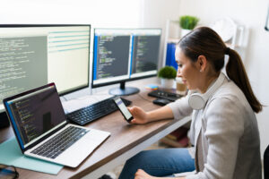 A person working at the desk with multiple monitors on it and with codes on their screens